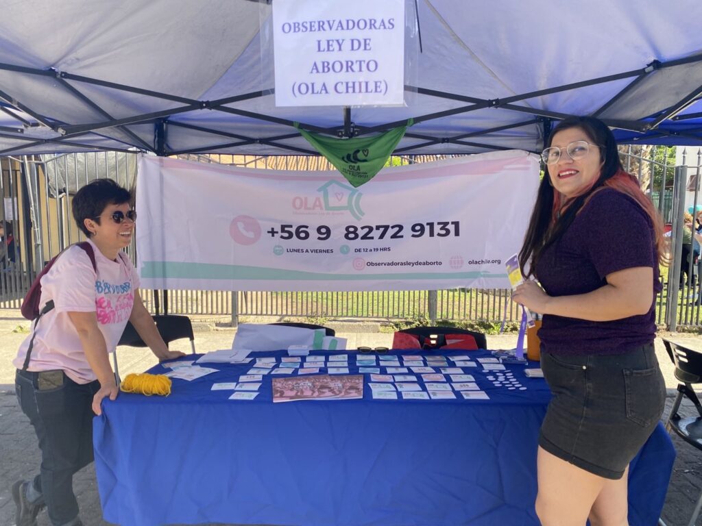 Profesional de OLA Chile entregan información a mujer en feria territorial